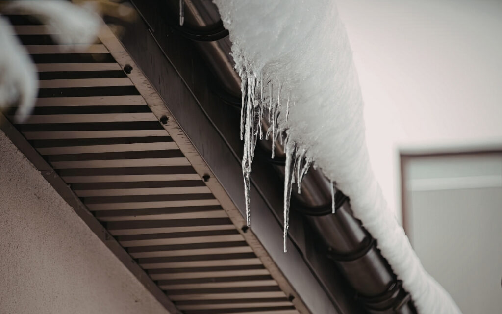 Gutter with snow piled up and icicles hanging from it