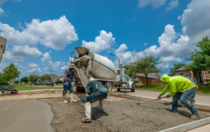 Concrete truck and crew pouring concrete and smoothing it out
